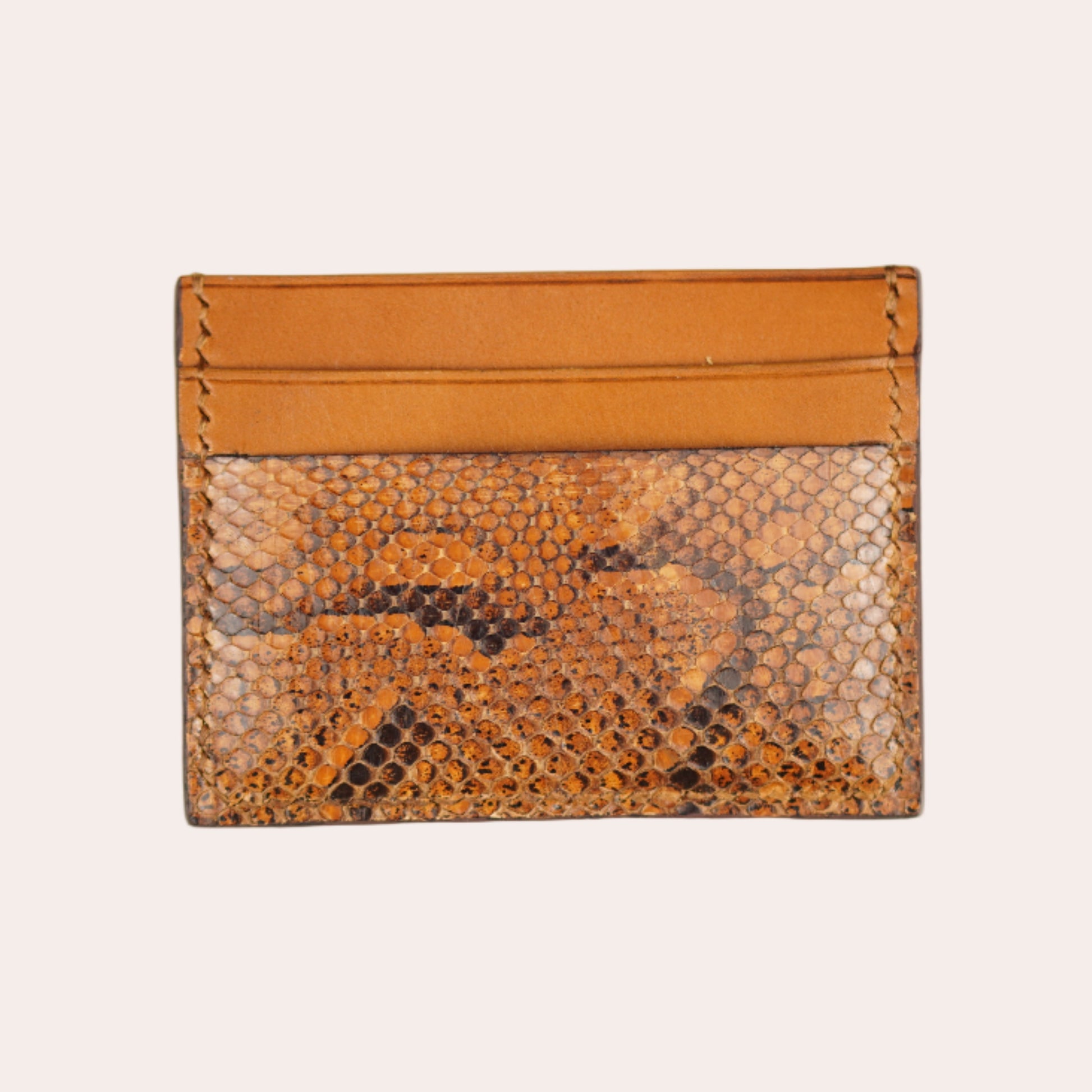 Snake skin patterned cardholder with orange top section on a beige background