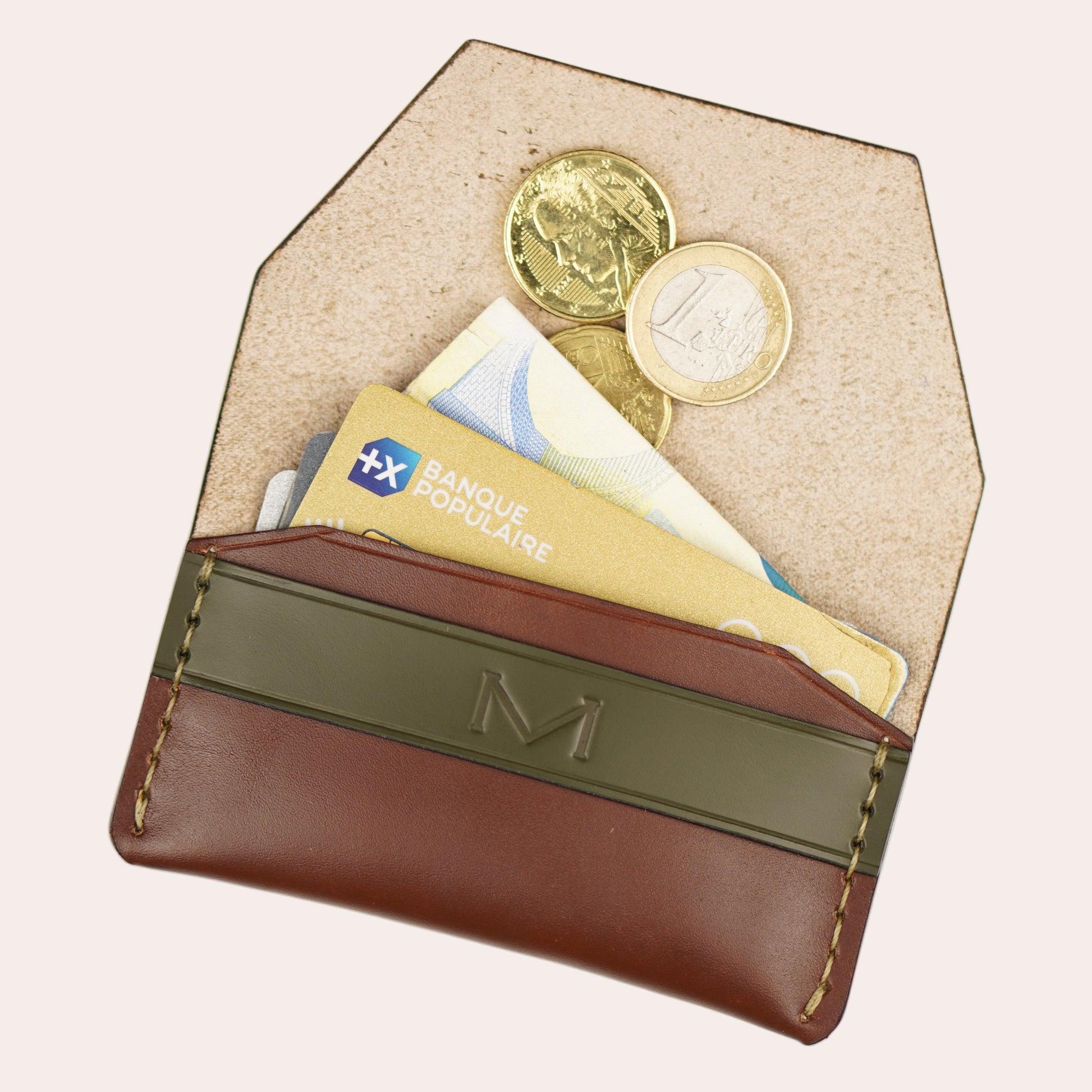 Beige wallet with brown flap containing coins and cards on a white background