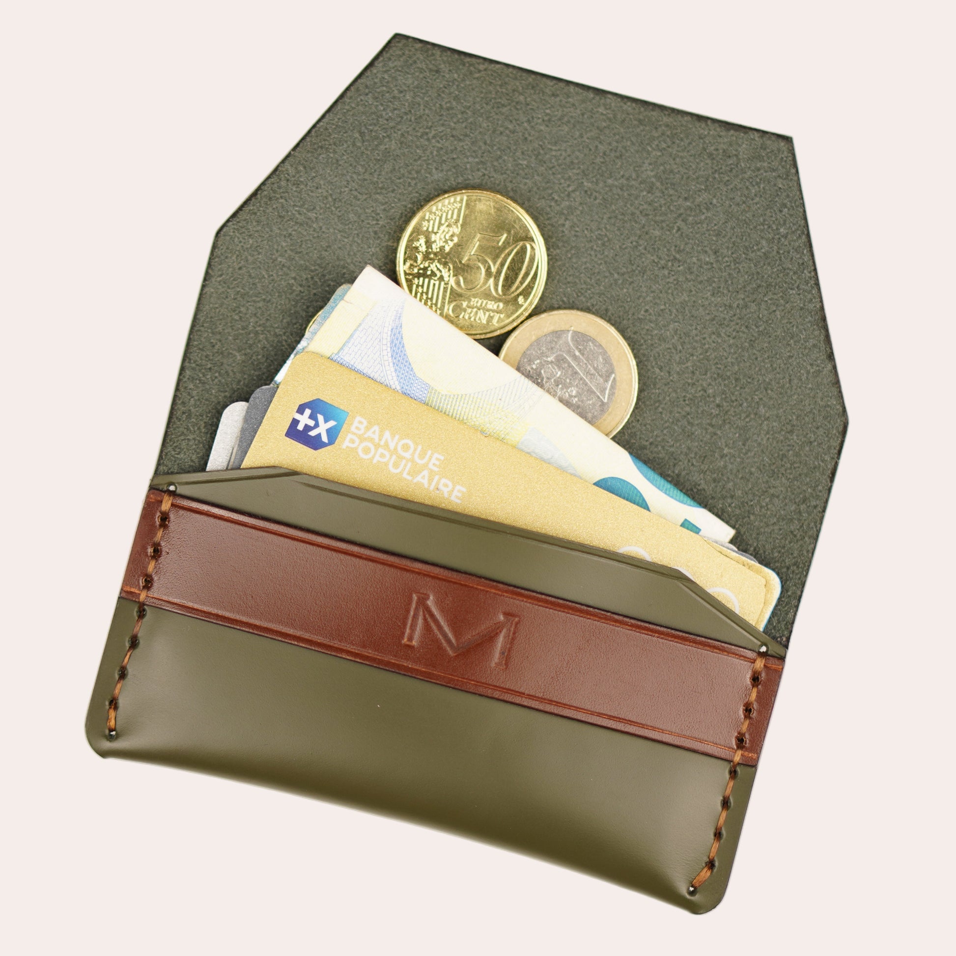 Green wallet with brown leather strap holding currency and coins on a white background
